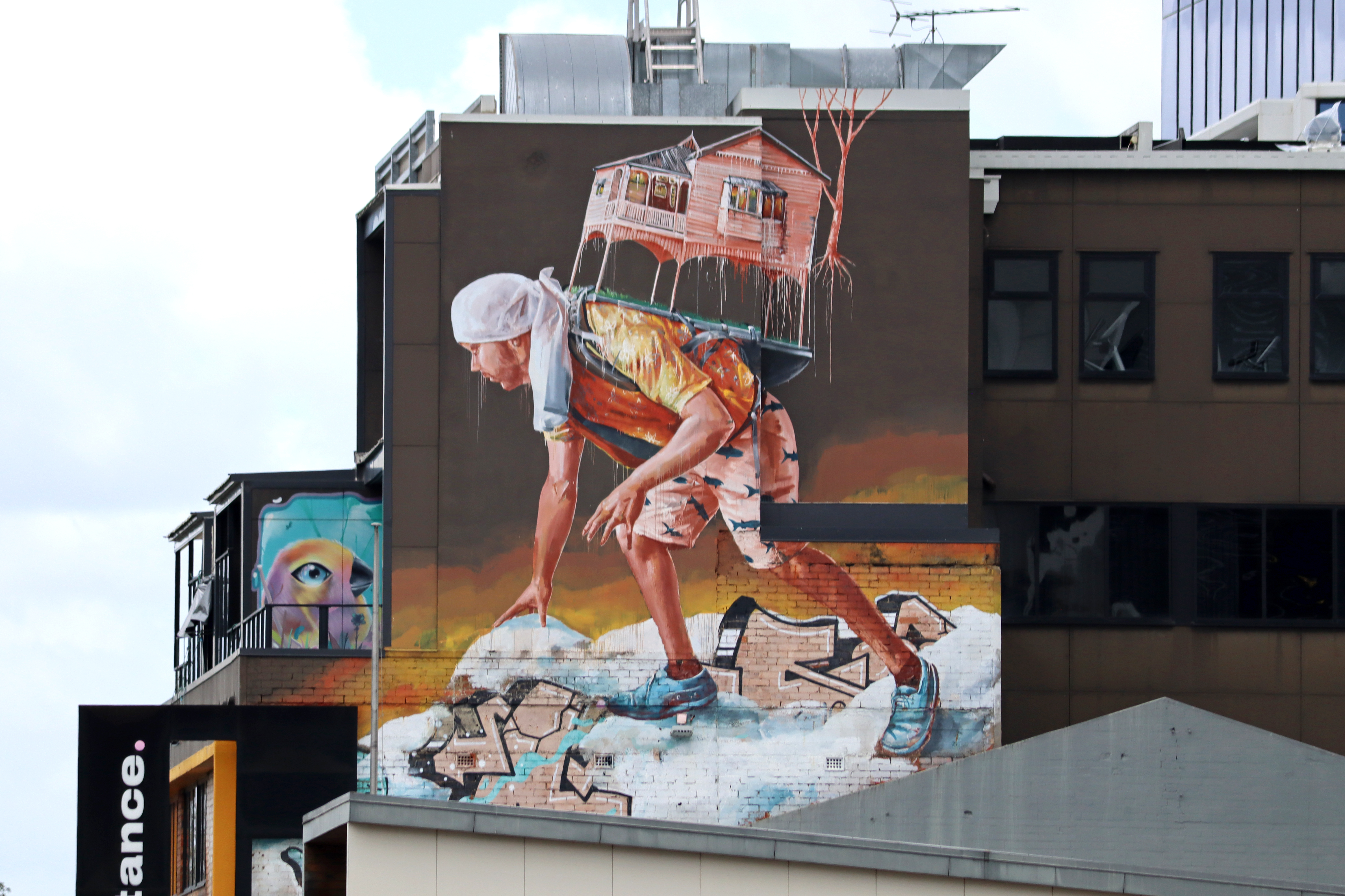Carrying a Queenslander through the snow in a shirt and shorts by Fintan Magee | Street Art NSW
